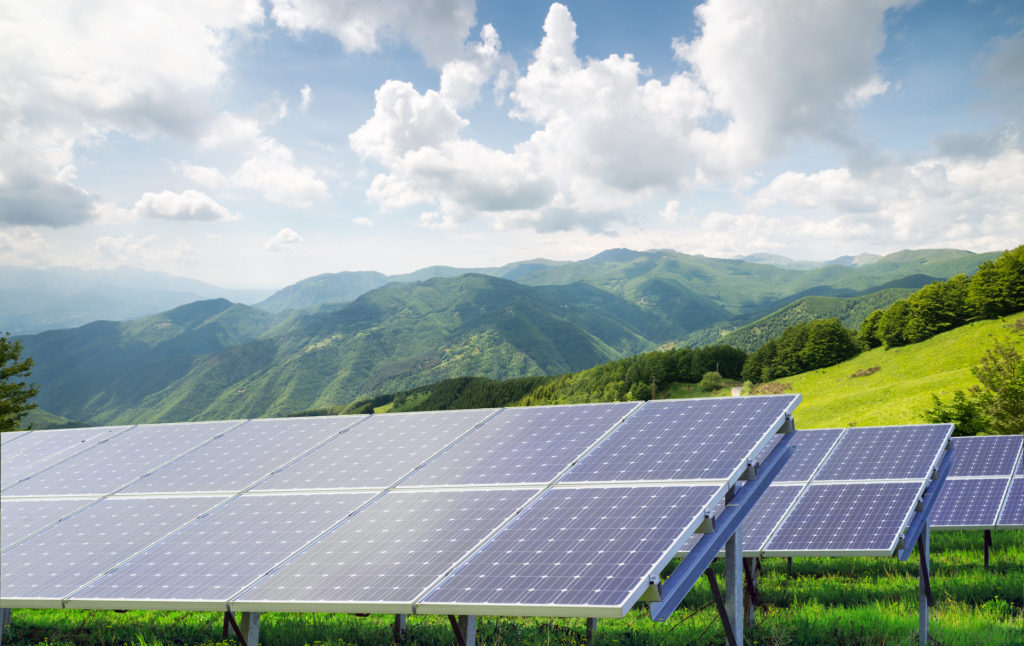 solar panels on a sunny day with mountains behind them