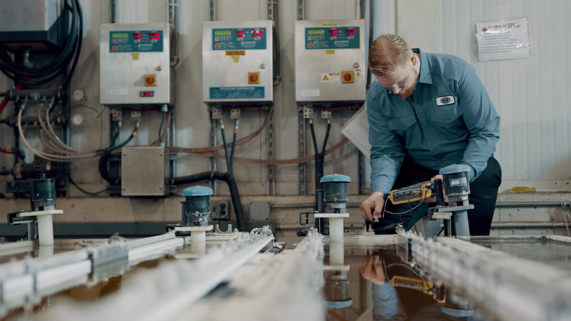 Person bending over with testing equipment to perform rectifier maintenance