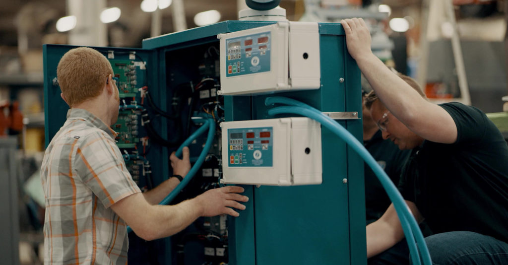 Person in plaid shirt working on rectifier with blue tubes