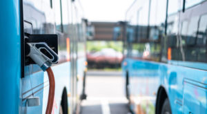 Two blue buses with EV charger plugged in on the left