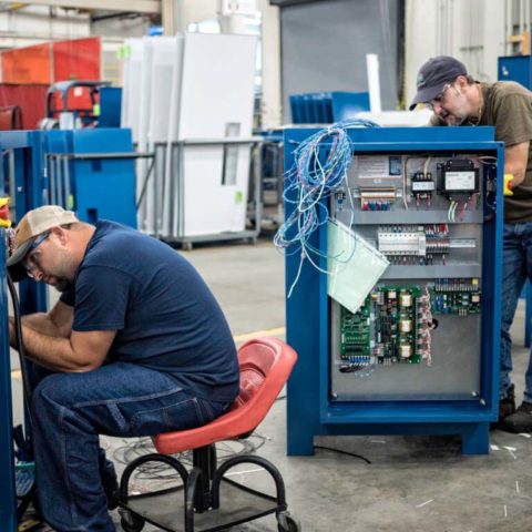 two people performing rectifier maintenance inside facility