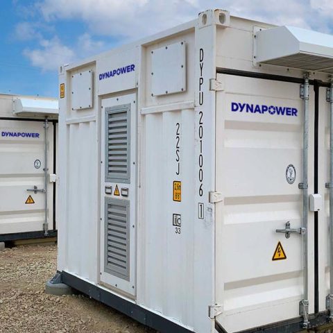 Row of five white Dynapower energy storage systems in desert