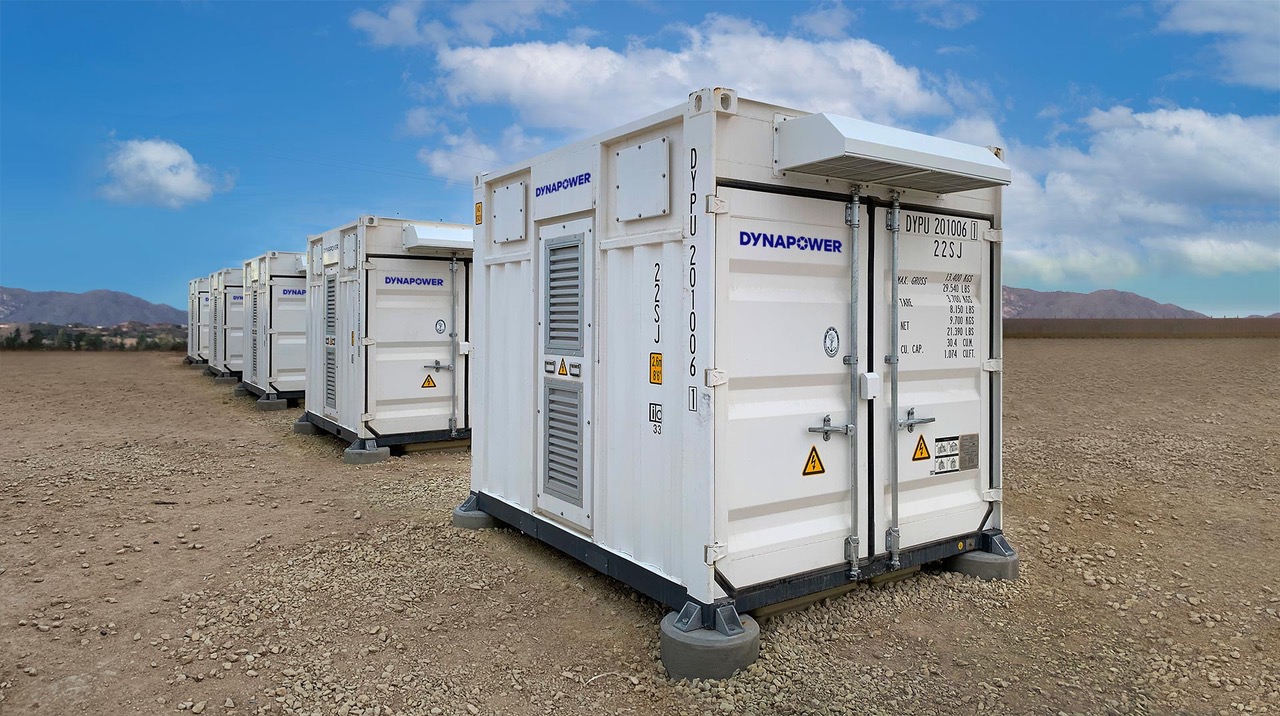 Row of five white Dynapower energy storage systems in desert